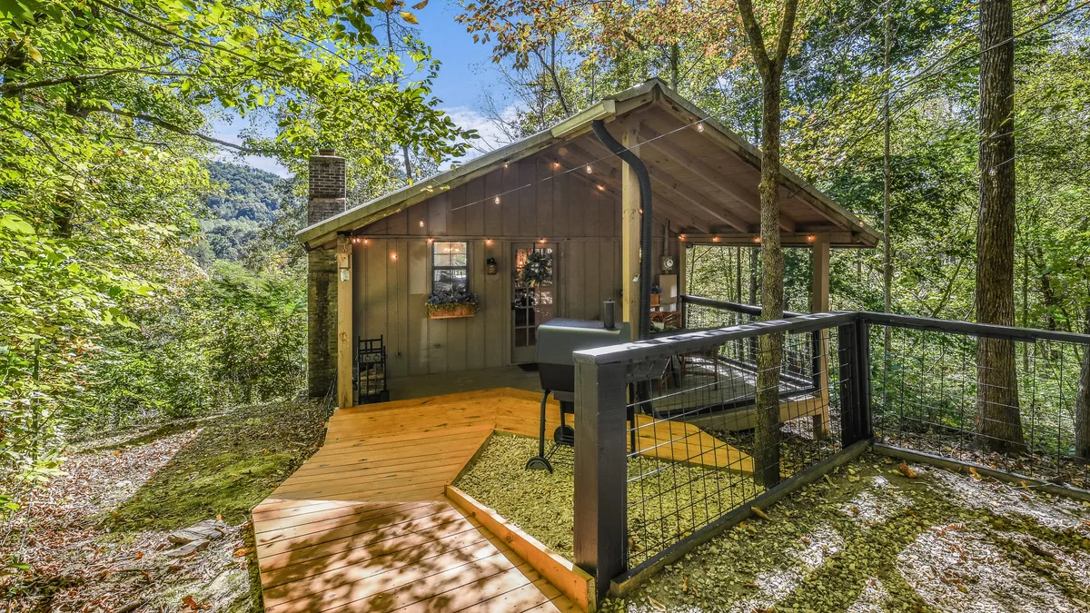 A tranquil wooden deck wrapped in string lights, surrounded by trees with comfortable outdoor seating that invites guests to relax, dine, or stargaze. The scene captures the serenity and magic of evenings spent outdoors after a day of adventure.